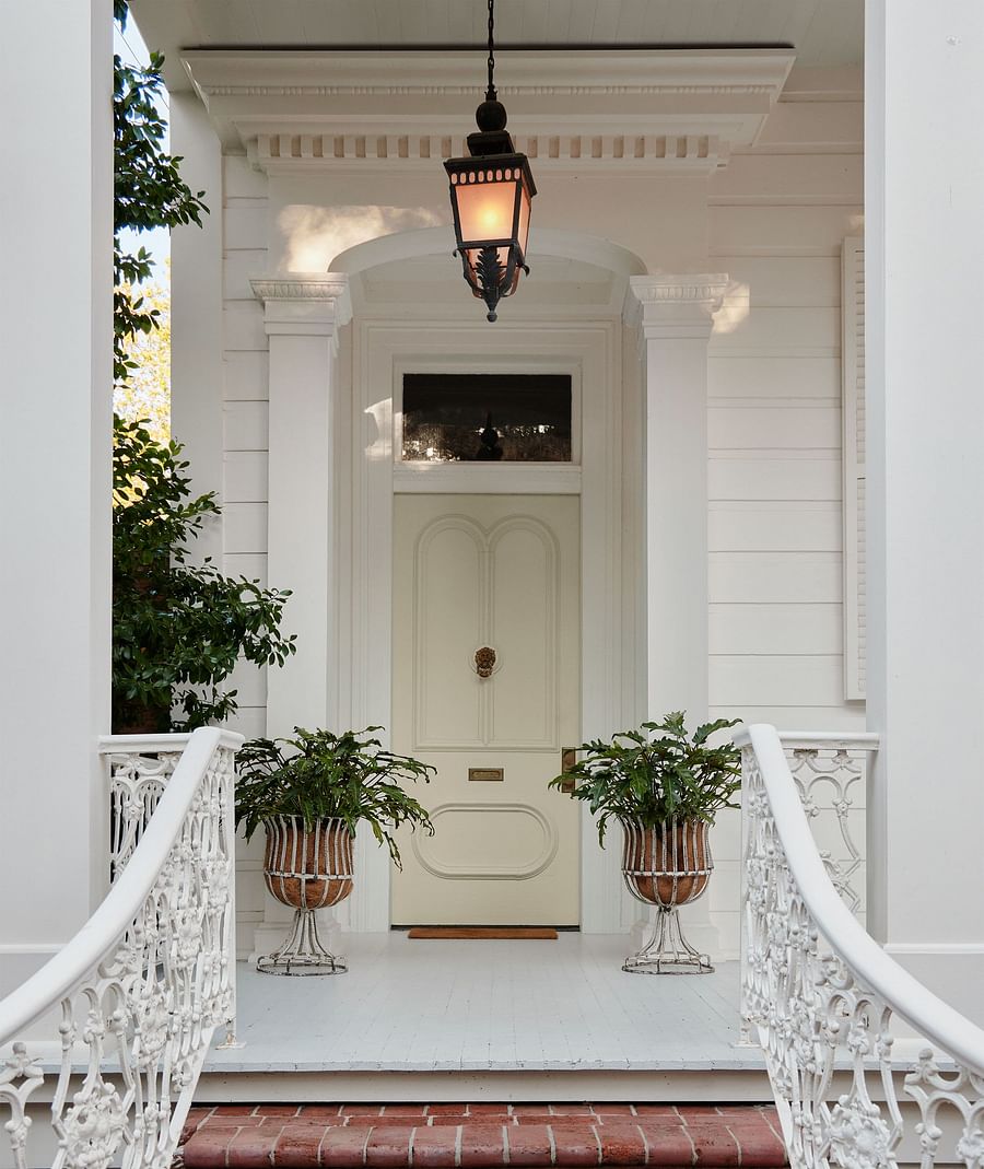 Serene garden oasis with lush greenery behind an elegant historic New Orleans mansion
